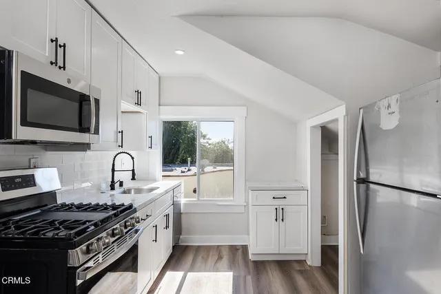 a kitchen with stainless steel appliances a stove a microwave and a window