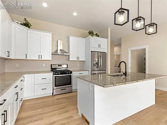 a kitchen with stainless steel appliances granite countertop a stove a sink dishwasher and white cabinets with wooden floor