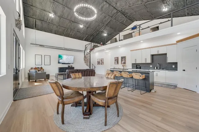 a kitchen with stainless steel appliances granite countertop a stove top oven a sink dishwasher a dining table and chairs with wooden floor