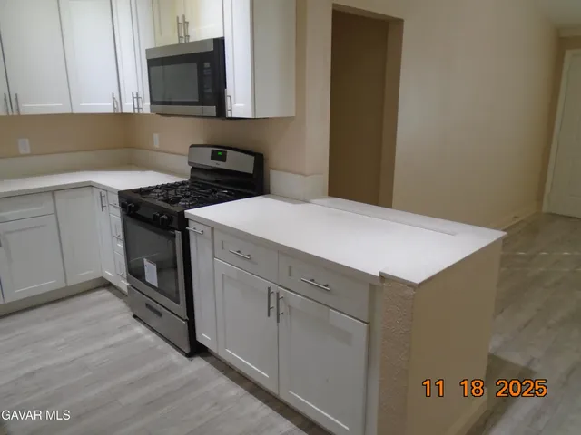 a kitchen with granite countertop cabinets stainless steel appliances and wooden floor