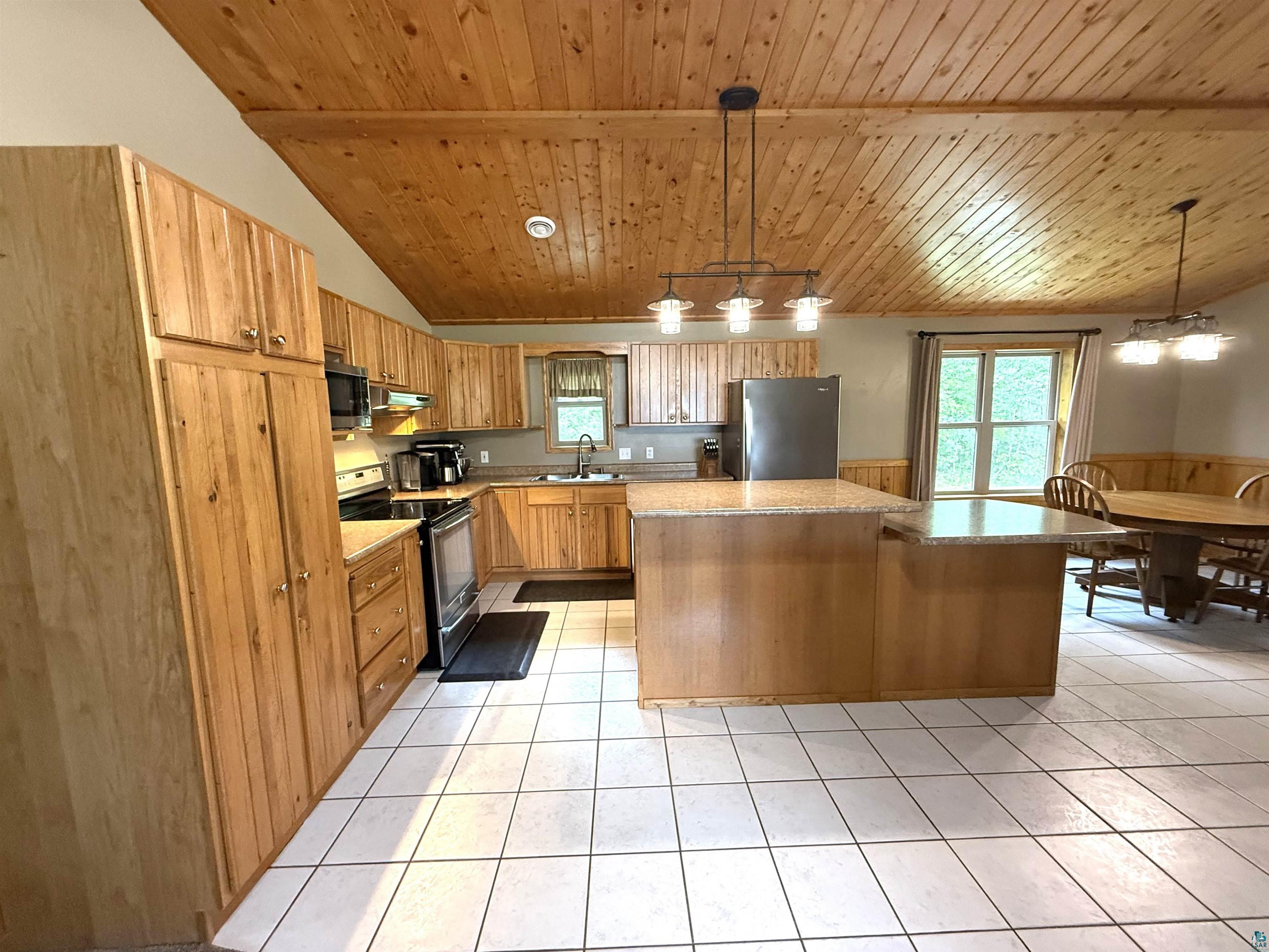 5080 Tower Road Moose Lake, MN 55767 - Photo 13 of 49 Vaulted wood-paneled ceiling, wood-finish cabinetry, granite-finish countertops, central island, and ceramic tile flooring