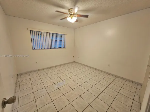 a view of an empty room and chandelier fan