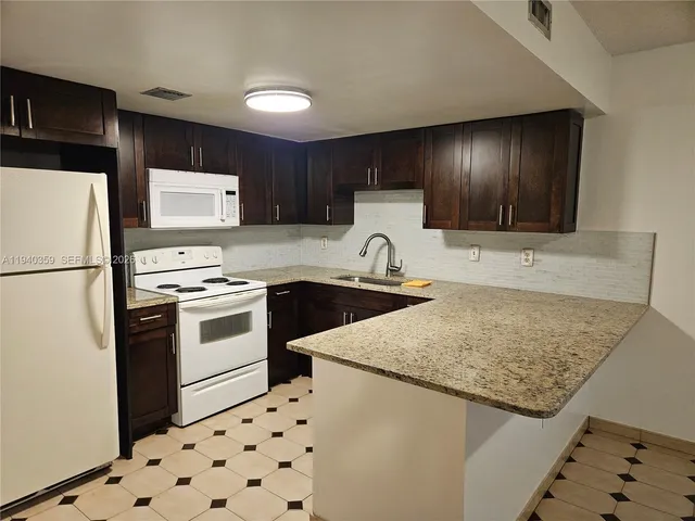 a kitchen with granite countertop a sink a stove and refrigerator