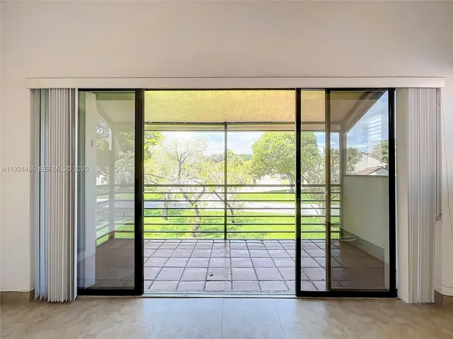 an empty room with chandelier fan and windows