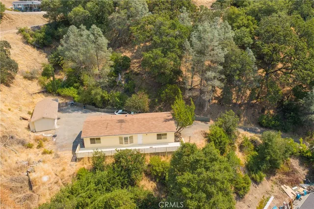 an aerial view of residential house with outdoor space and trees all around