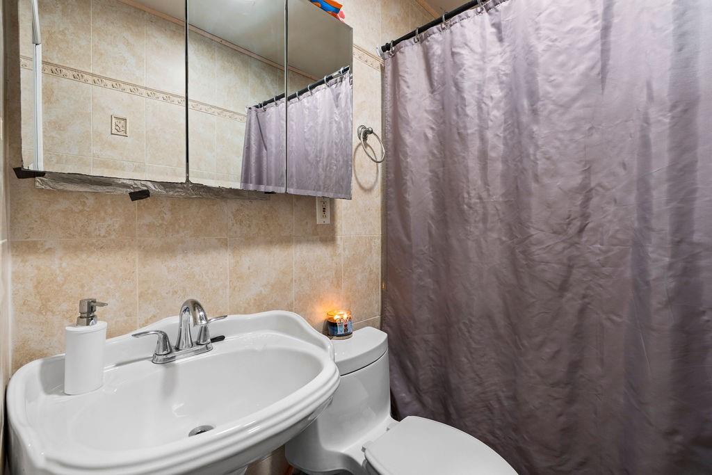 32 Brighton 2nd Place Brooklyn, NY 11235 - Photo 15 of 23 a bathroom with a sink a toilet and shower curtain