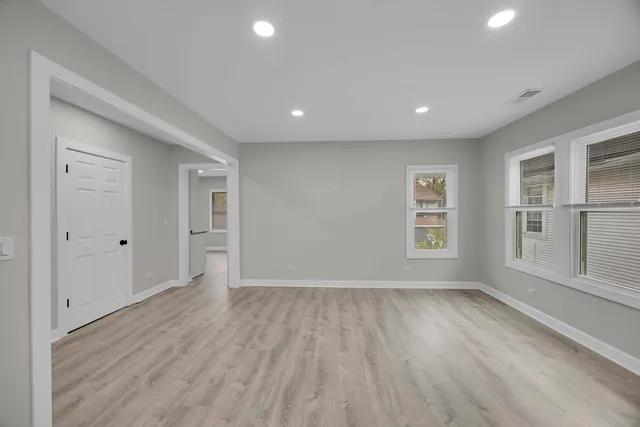 a view of empty room with wooden floor and fan