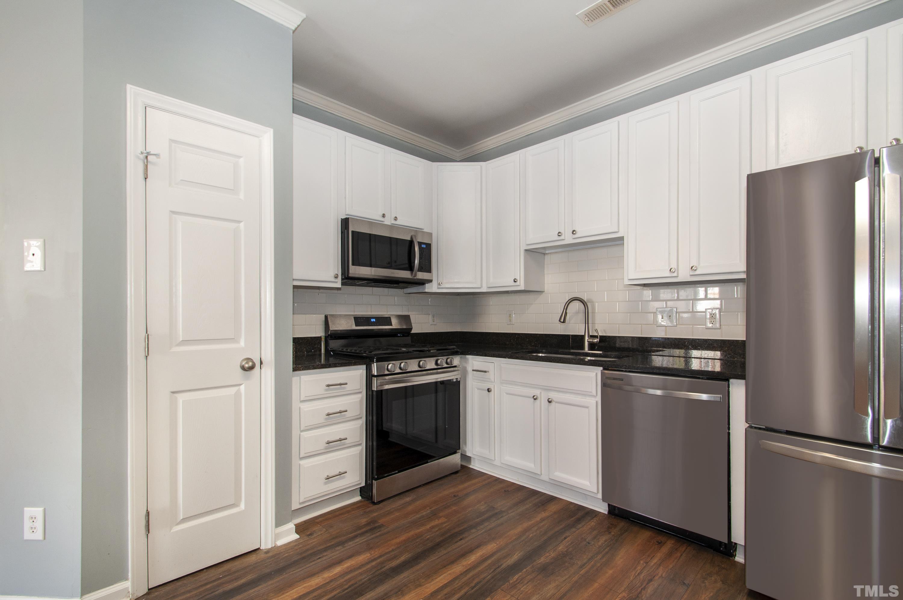 2210 Raven Road, Unit 102 Raleigh, NC 27614 - Photo 9 of 33 a kitchen with stainless steel appliances granite countertop a refrigerator stove a sink and dishwasher with wooden floor