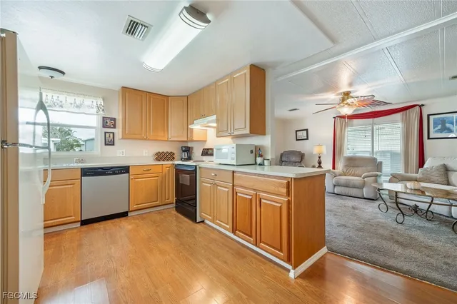 a kitchen with stainless steel appliances granite countertop a sink dishwasher a stove a refrigerator and island with wooden floor