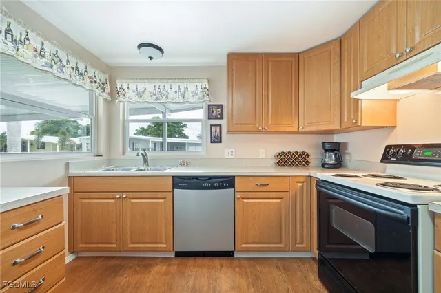 a kitchen with stainless steel appliances granite countertop a stove a sink and white cabinets with wooden floor