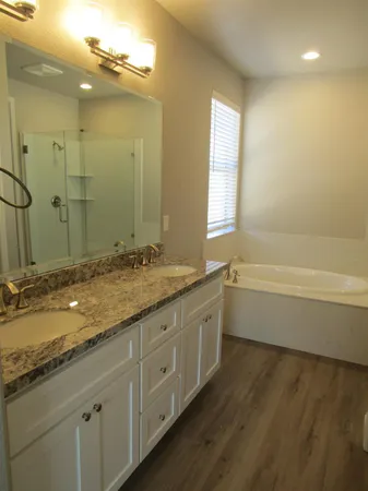 a bathroom with a granite countertop sink a large mirror a toilet and a bathtub