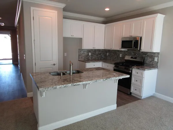 a kitchen with granite countertop a sink a stove and microwave
