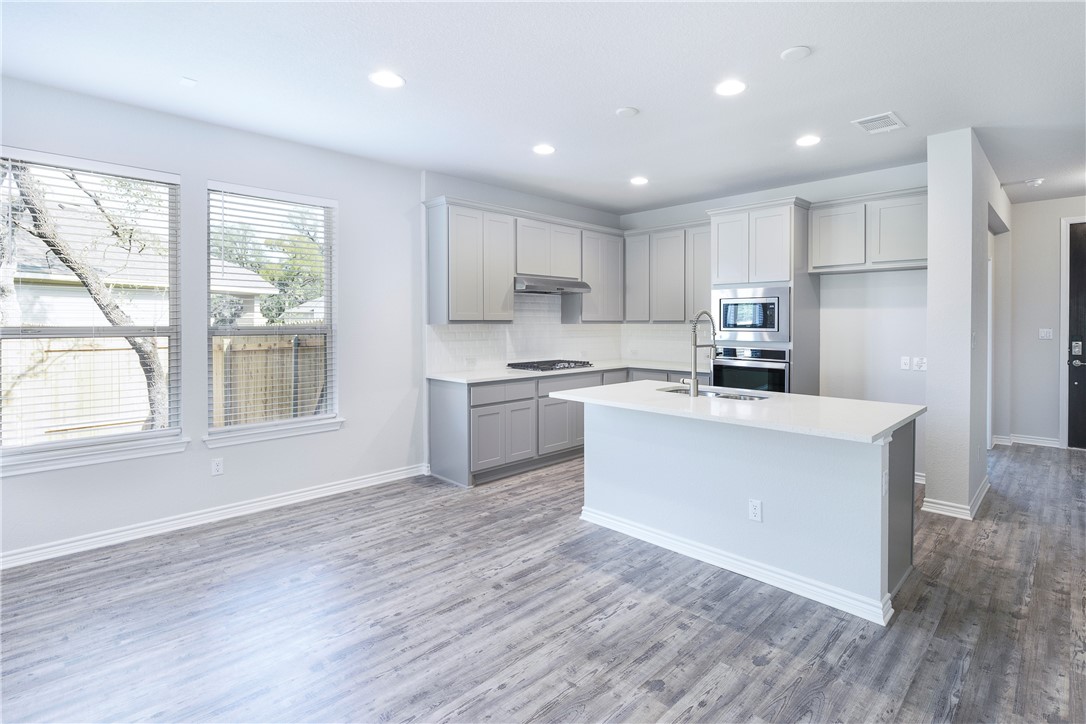 1613 Winding Stream Trail, Unit 75 Leander, TX 78641 - Photo 13 of 23 a kitchen with wooden floors and white stainless steel appliances