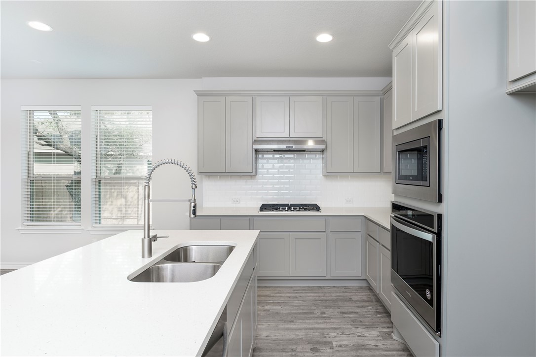 1613 Winding Stream Trail, Unit 75 Leander, TX 78641 - Photo 2 of 23 a kitchen with stainless steel appliances granite countertop a sink and a stove top oven