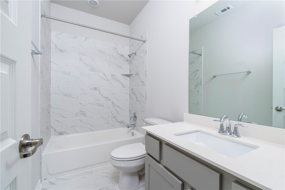 1613 Winding Stream Trail, Unit 75 Leander, TX 78641 - Photo 21 of 23 a bathroom with a granite countertop sink a toilet a mirror a bathtub and shower
