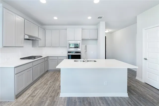 a kitchen with kitchen island a sink a stove a refrigerator and white cabinets
