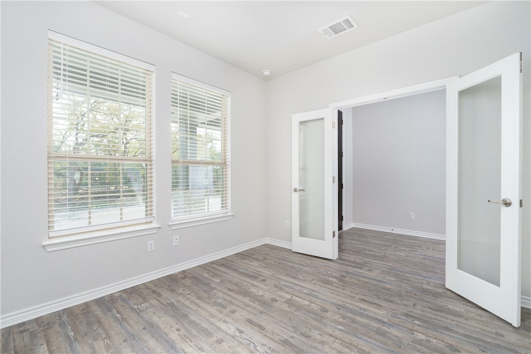 1613 Winding Stream Trail, Unit 75 Leander, TX 78641 - Photo 9 of 23 a view of an empty room with wooden floor and a window