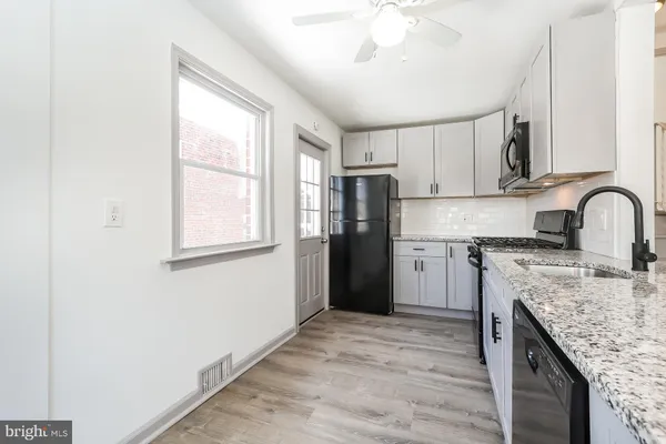 a kitchen with granite countertop a refrigerator stove sink and cabinets