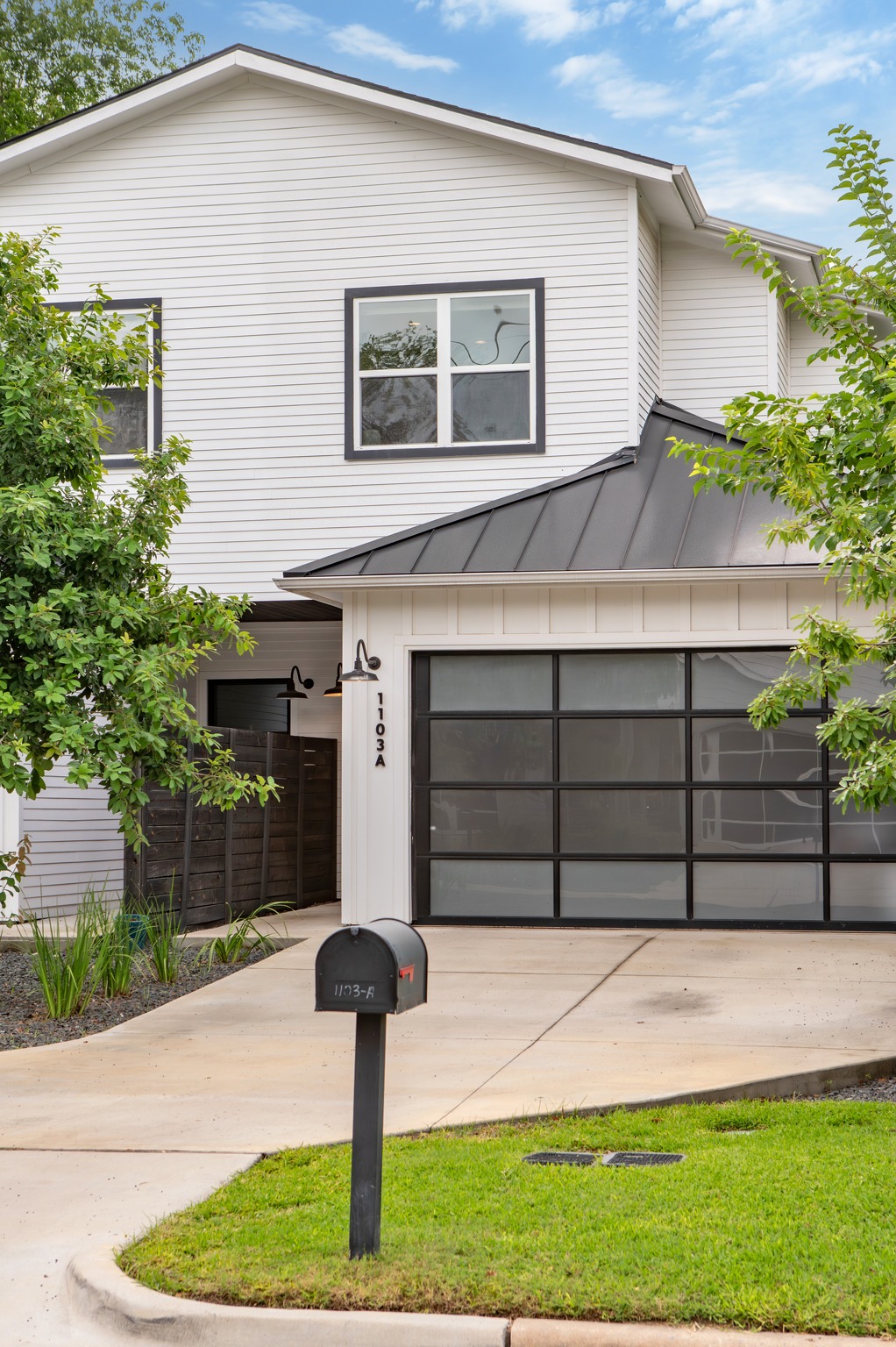 1103 Saucedo Street, Unit 1 Austin, TX 78721 - Photo 2 of 40 A striking contemporary residence boasts a sleek garage door and crisp white siding under a modern black roof.