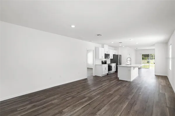 a view of kitchen with kitchen island wooden floors and stainless steel appliances