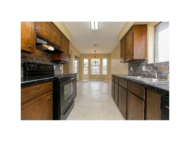 a kitchen with granite countertop a stove a sink and a refrigerator
