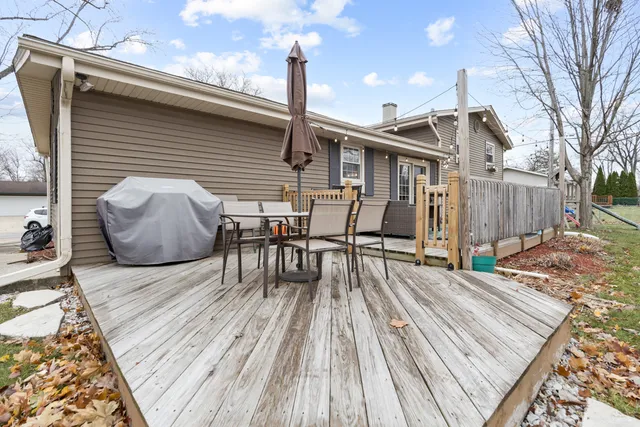 a view of a roof deck with table and chairs with wooden floor and fence