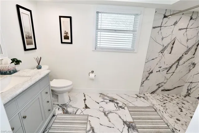 a bathroom with a granite countertop toilet sink and mirror