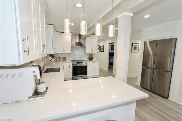 a large white kitchen with stainless steel appliances granite countertop a stove a sink dishwasher and white cabinets with wooden floor