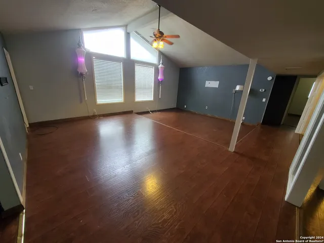 an empty room with wooden floor and windows