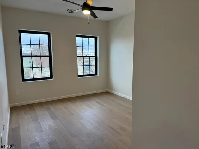 a view of a hallway with wooden floor and a bathroom