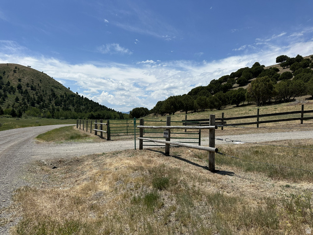2006 Swenson Valley Road Bancroft, ID 83217 - Photo 47 of 51 Gravel road entry featuring a rustic wood fence and metal gate, bordering a grassy area with distant hills and mature trees