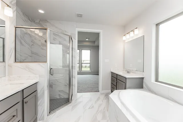 a spacious bathroom with a tub sink and mirror