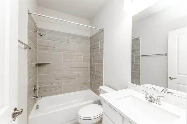 a bathroom with a bathtub shower sink vanity mirror and toilet
