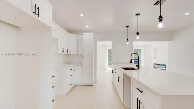 a kitchen with white cabinets and sink