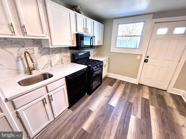 a kitchen with granite countertop a sink dishwasher stove and cabinets