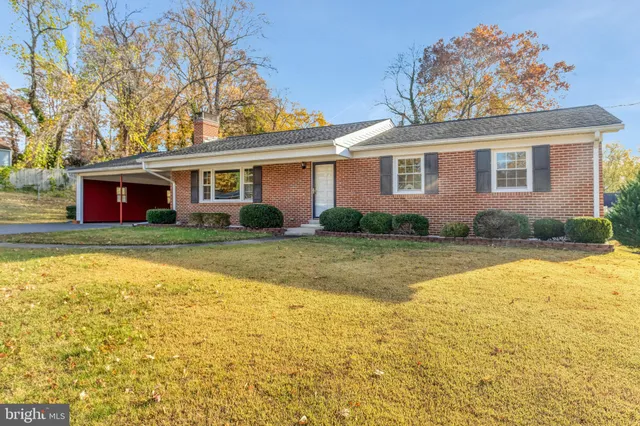 a front view of house with yard and trees in the background