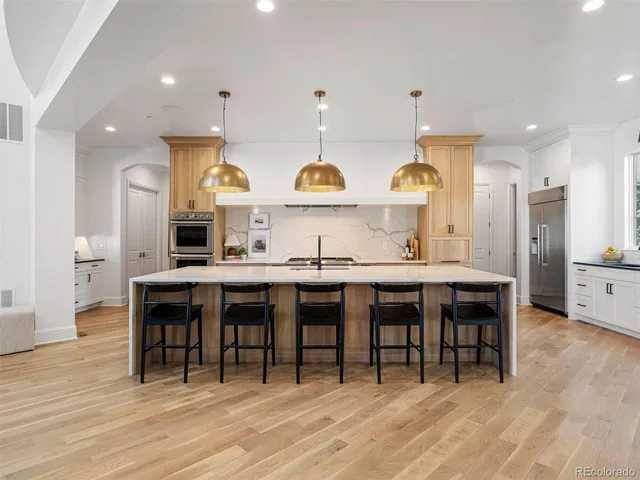 a kitchen with stainless steel appliances kitchen island granite countertop a table chairs sink and cabinets