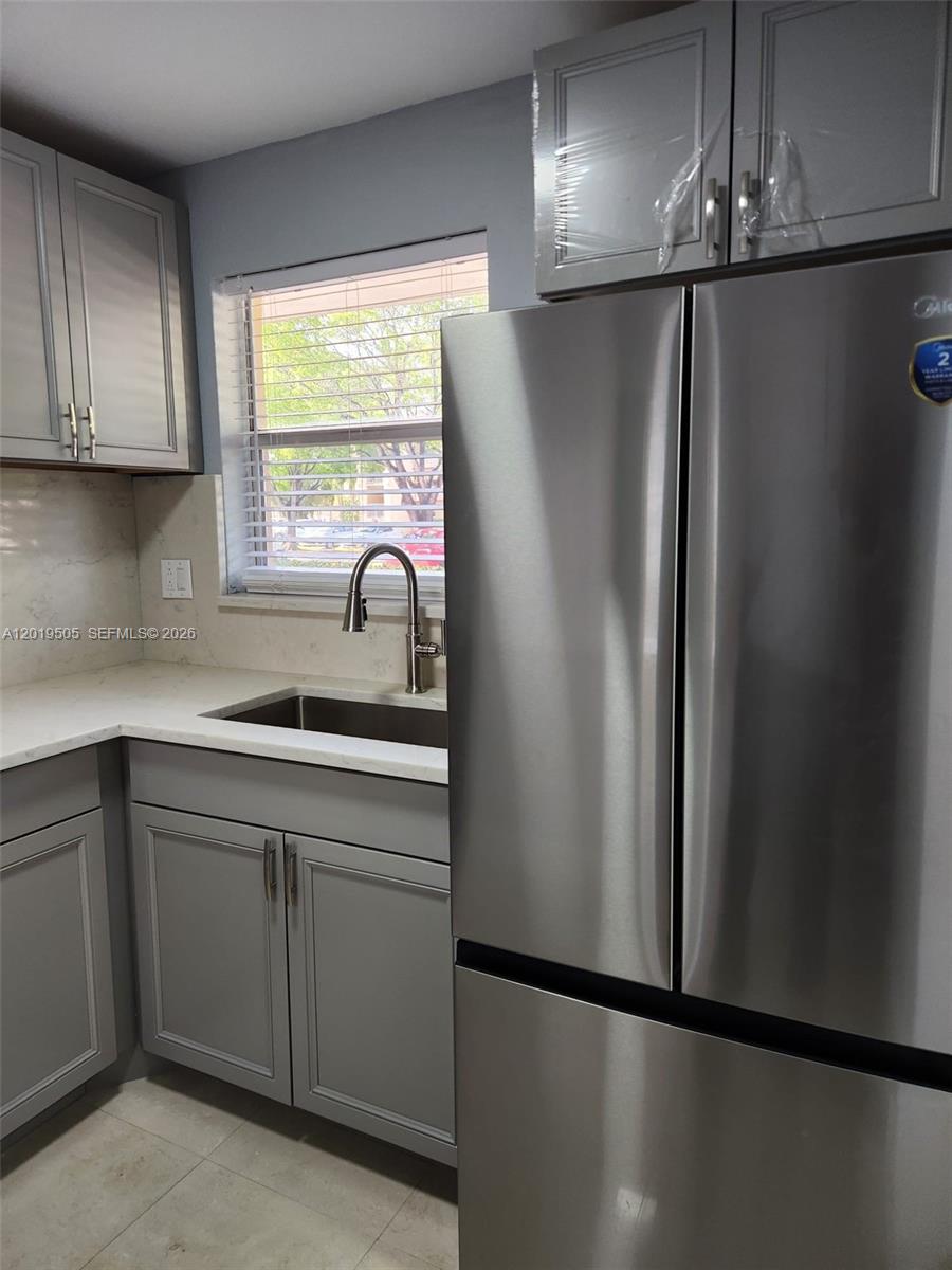 2811 North Pine Island Road, Unit 107 Sunrise, FL 33322 - Photo 3 of 16 a kitchen with refrigerator a sink and cabinets