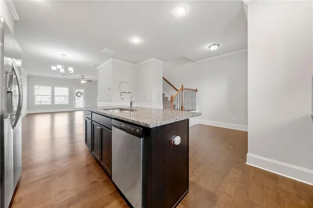 a kitchen with stainless steel appliances granite countertop a sink a stove and a wooden floors