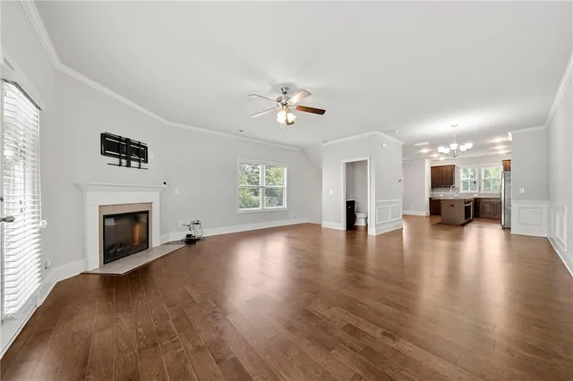 a view of a livingroom with a fireplace a ceiling fan and windows