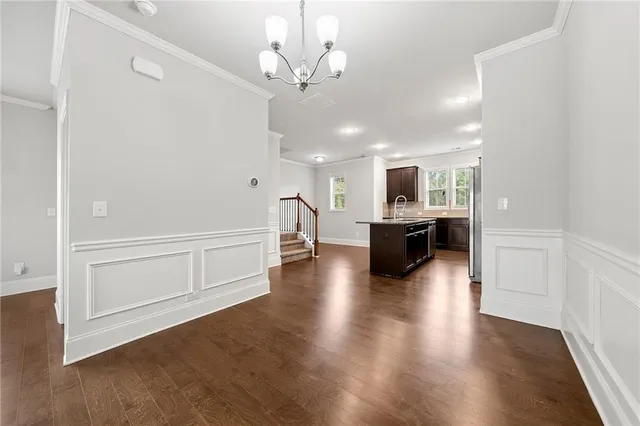 a view of a hallway with wooden floor and a kitchen