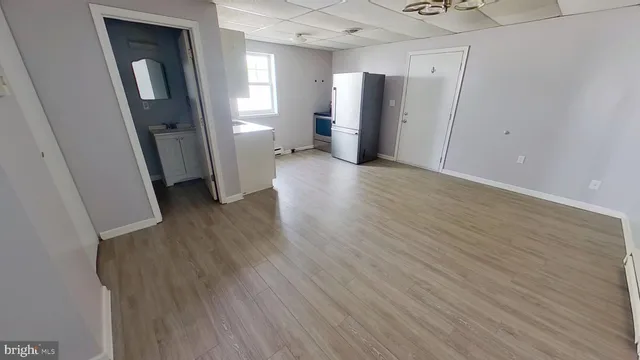 a view of a hallway with wooden floor and a refrigerator