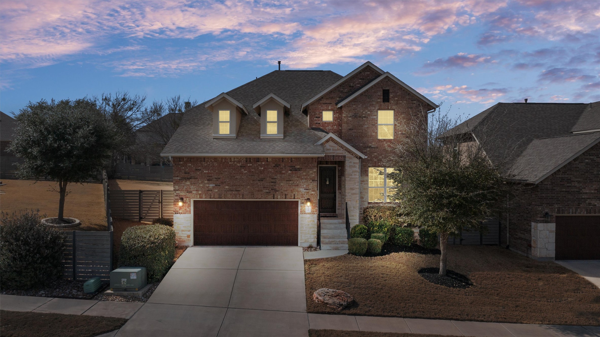 4216 Mercer Road Georgetown, TX 78628 - Photo 3 of 40 Front of home featuring warm exterior lighting, a spacious driveway leading to a two-car garage, and a covered front entry