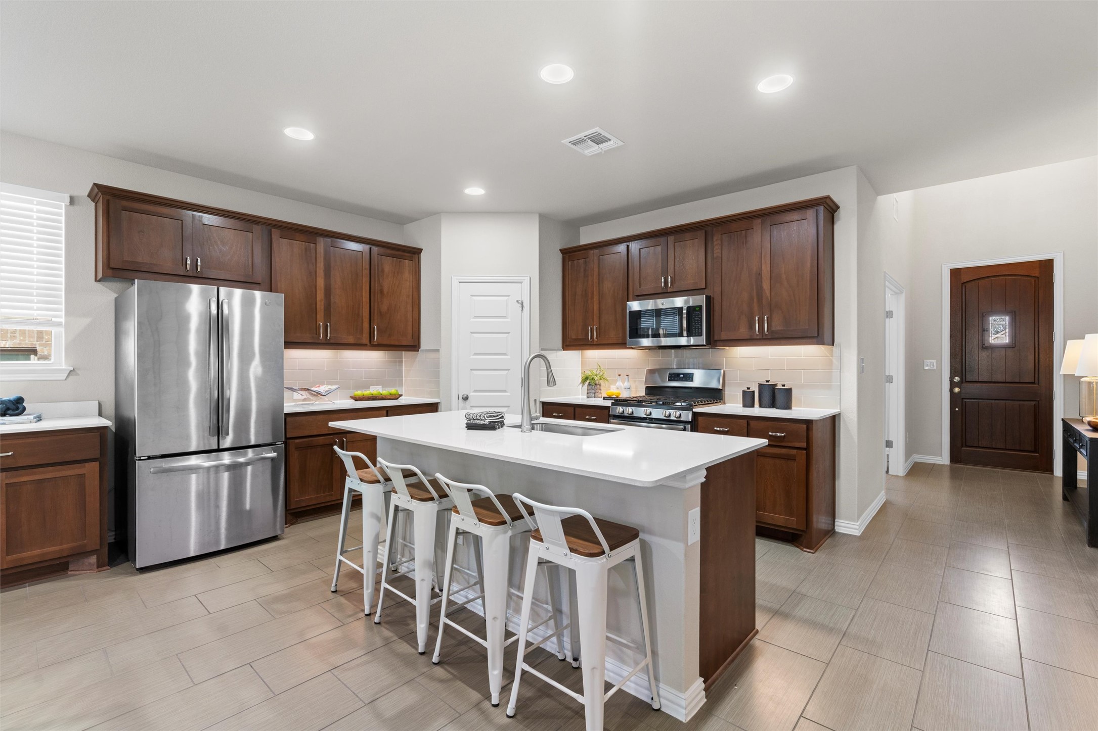 4216 Mercer Road Georgetown, TX 78628 - Photo 7 of 40 Kitchen featuring stainless steel appliances, a kitchen bar, a kitchen island with sink, decorative backsplash, and dark wood finish cabinets