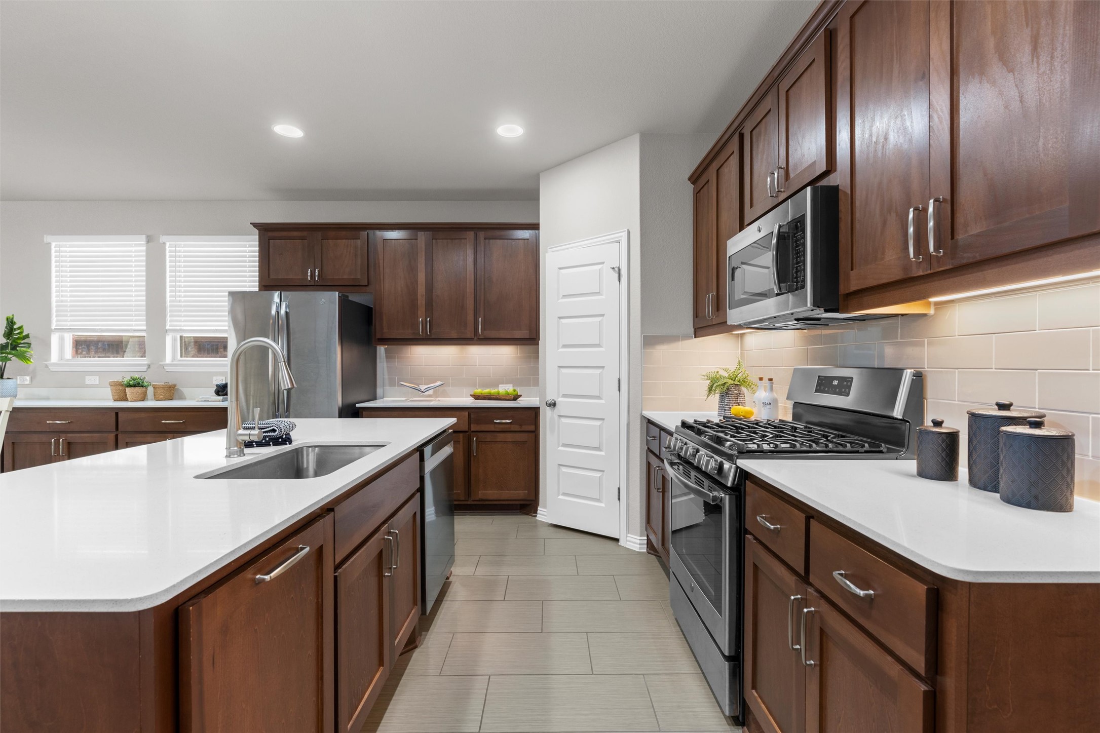 4216 Mercer Road Georgetown, TX 78628 - Photo 9 of 40 Kitchen featuring stainless steel appliances, an island with sink, dark wood finish cabinetry, recessed lighting, and light tile patterned floors