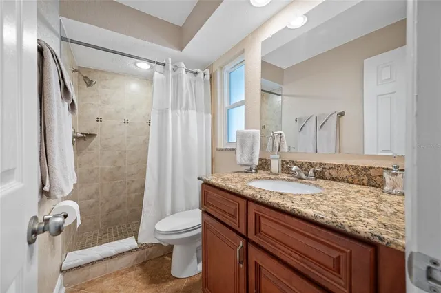 a bathroom with a granite countertop sink toilet and shower