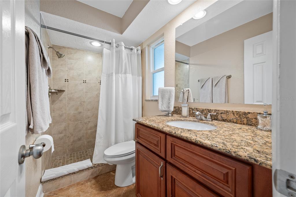 12957 90th Terrace Seminole, FL 33776 - Photo 21 of 31 a bathroom with a granite countertop sink toilet and shower