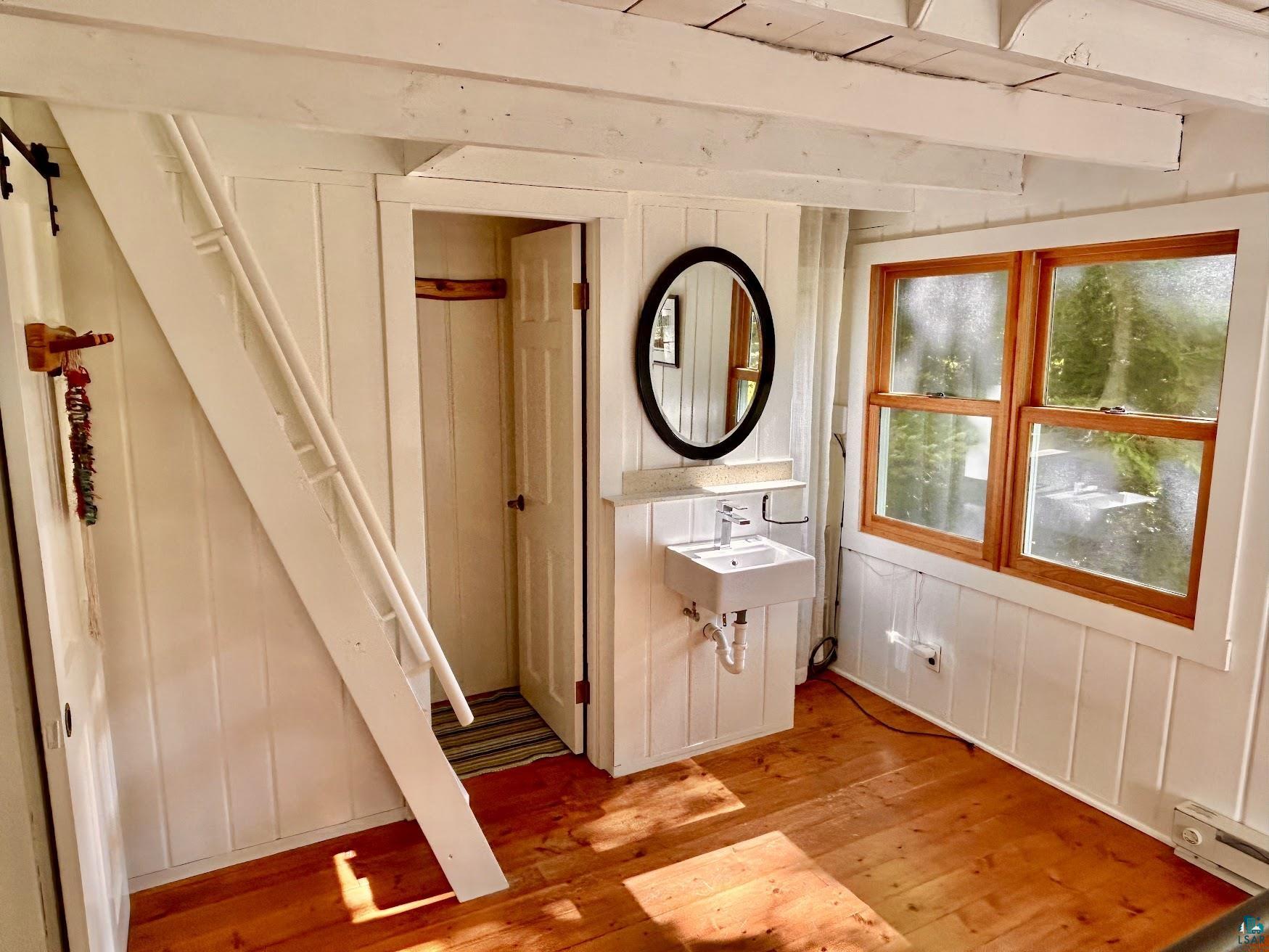 1596 North Shore Road La Pointe, WI 54850 - Photo 6 of 21 Bright interior space featuring wood-finish flooring, white paneled walls, and exposed ceiling beams