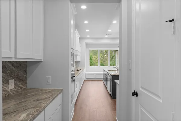 a kitchen with white cabinets and a wooden floor