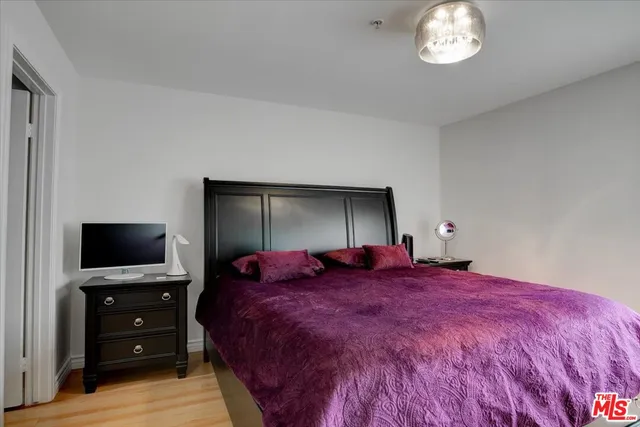 a bedroom with a bed and a flat tv screen on dresser